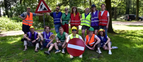 Kampleiding poseert vrolijk in verkeershesjes en bouwhelmen in het bos.