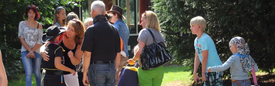 Ouders nemen warm afscheid van hun kinderen bij het kampgebouw
