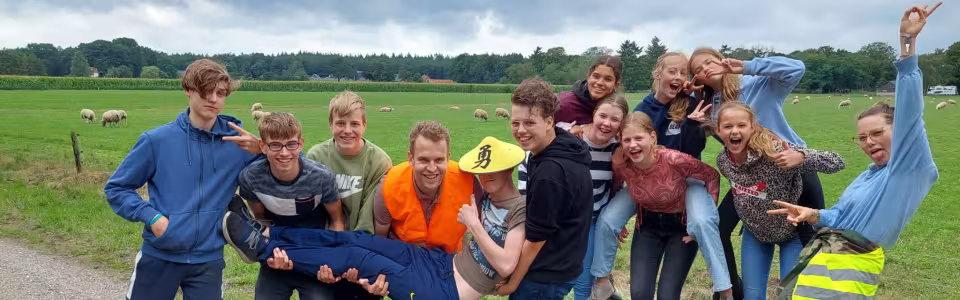 Groep deelnemers doet gek voor de camera op een landweg