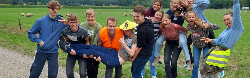 Groep deelnemers doet gek voor de camera op een landweg
