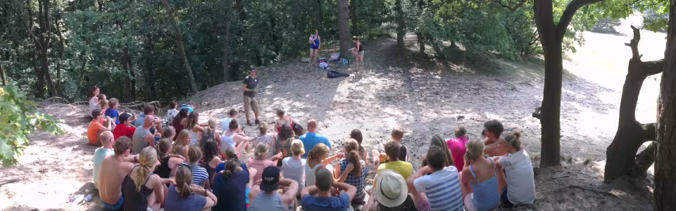 Grote groep deelnemers op het grasveld bij het speelveld