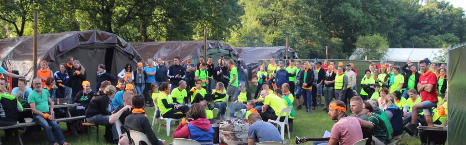 Deelnemers zitten op stoelen buiten voor de tent