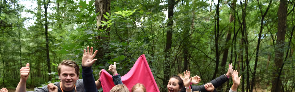 Kampleider en kinderen juichen in het bos
