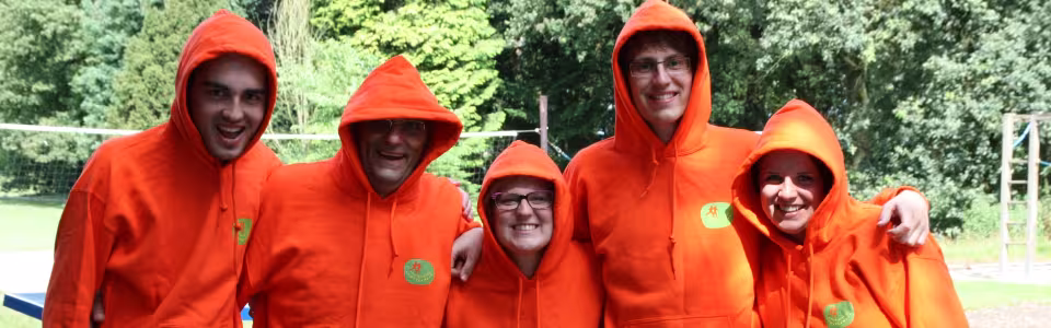 Vier kampleiders in oranje regenpakken