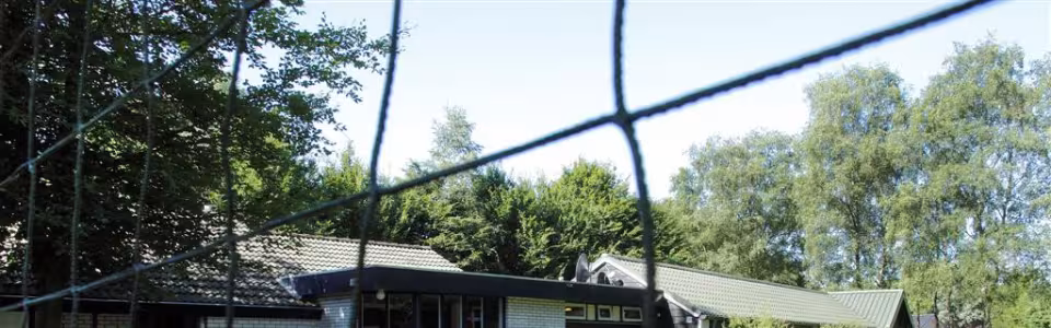 Kampgebouw achter een sportveld met net