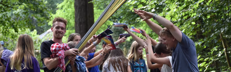 Deelnemers spelen een spel met stokken en linten