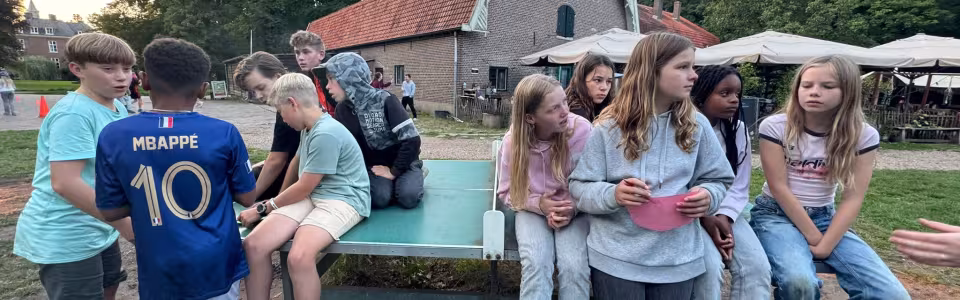 Deelnemers zitten op opblaasbare kussens bij het gebouw