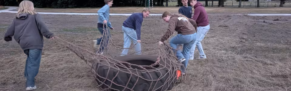 Deelnemers slepen een grote band over het veld