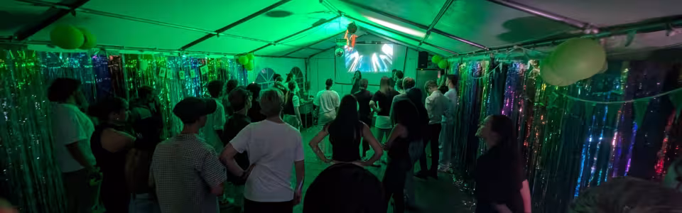 Deelnemers dansen in een tent met groen licht
