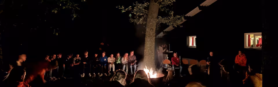 Deelnemers rond een kampvuur in het donker