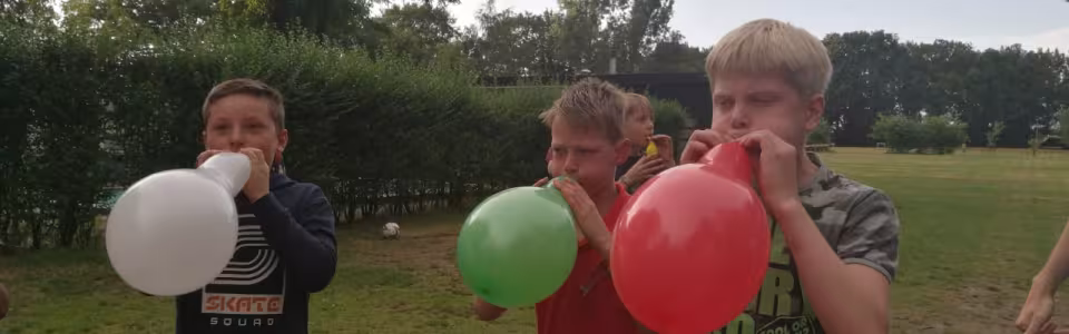 Kinderen blazen ballonnen op in het gras