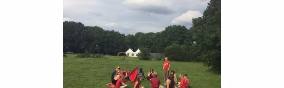 Deelnemers zitten in een kring op een grasveld