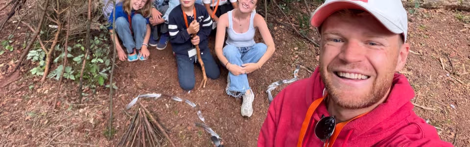 Kampleider maakt een selfie met deelnemers bij een hut