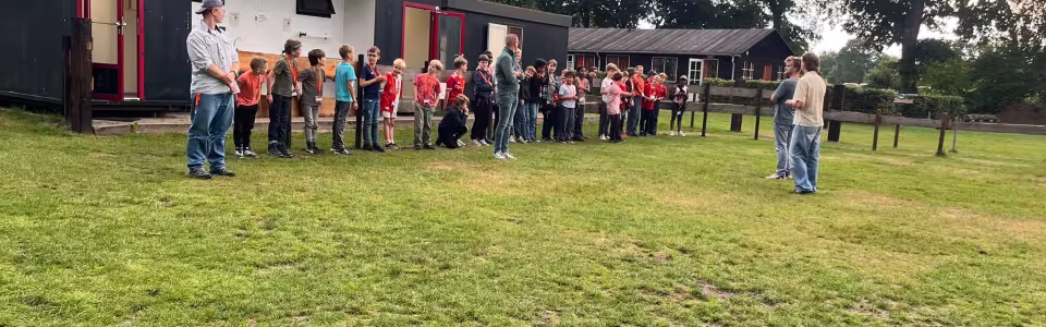 Deelnemers verzamelen zich op het grasveld bij het gebouw