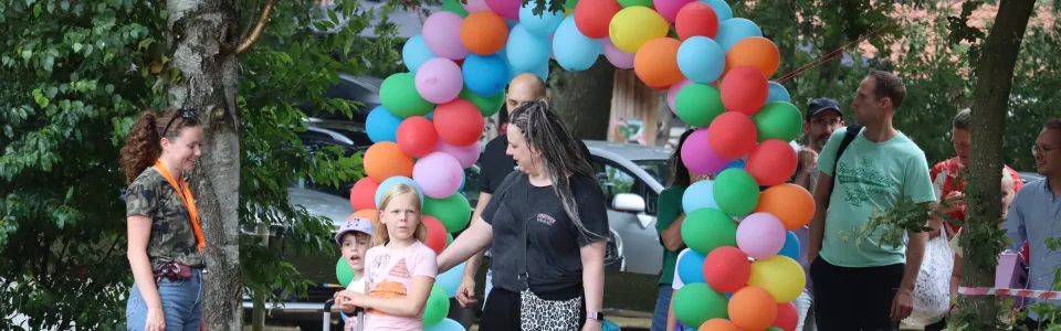 Kinderen arriveren met koffers onder een kleurrijke ballonnenboog