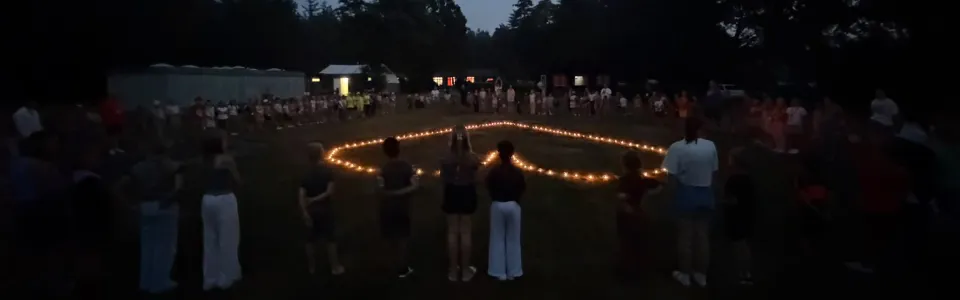 Kinderen staan in een kring rond een verlicht hart bij schemering