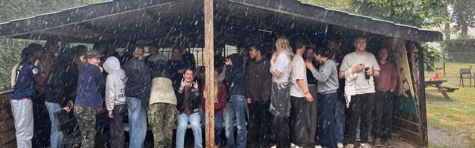 Tieners schuilen lachend onder een afdak tijdens een stortbui