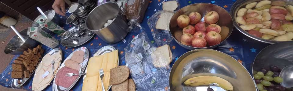 Leiding bereidt een uitgebreid ontbijt met brood, fruit en beleg voor