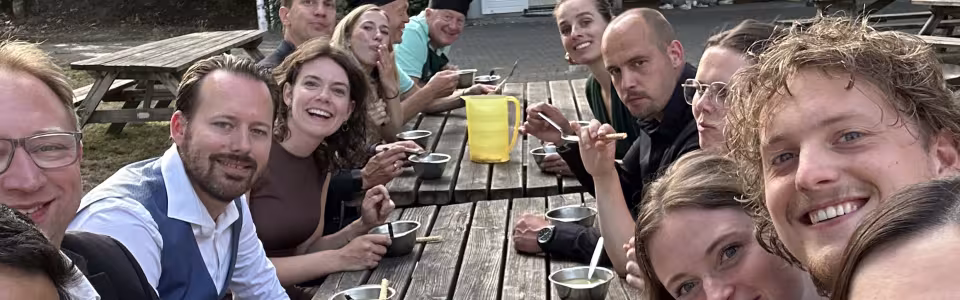 Kampleiding geniet samen van soep aan een lange picknicktafel