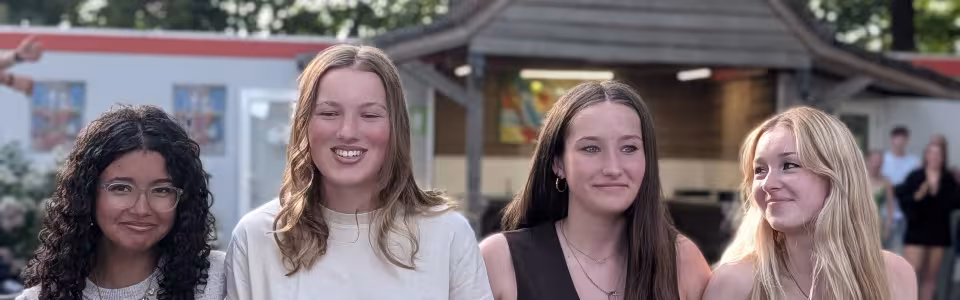 Vier tienermeiden staan lachend samen op het zomerkampterrein