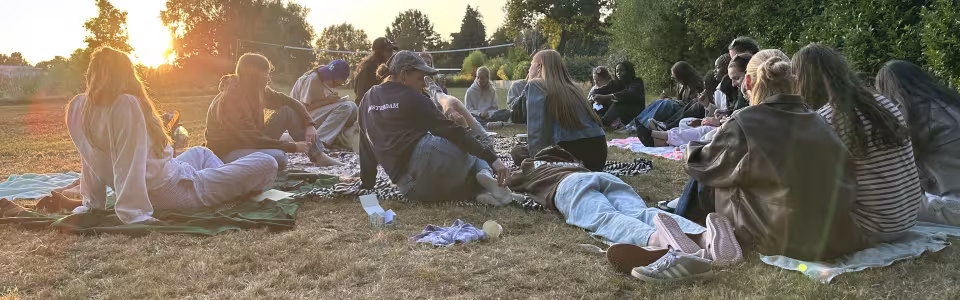 Tieners zitten samen op dekens tijdens een zonnige kampavond
