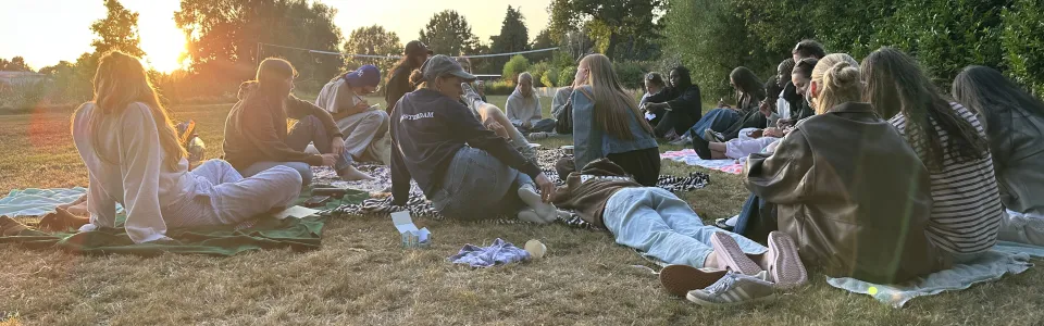 Tieners zitten samen op dekens tijdens een zonnige kampavond