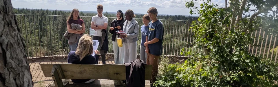 Tieners luisteren samen naar uitleg op een zonnig uitzichtpunt