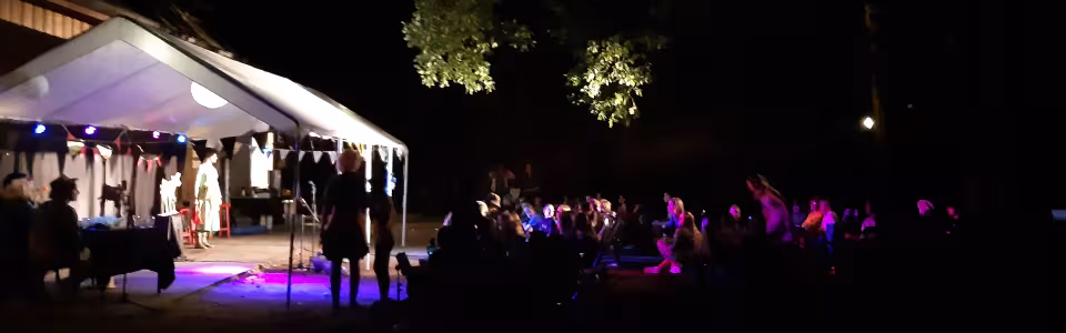 Avondprogramma in een verlichte partytent op het kampterrein