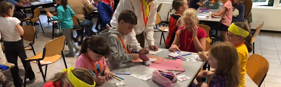 Kinderen knutselen aan tafels in de zaal