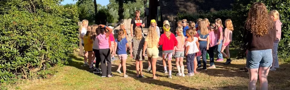 Kinderen verzamelen bij een leider voor een activiteit in de ochtendzon