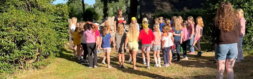 Kinderen verzamelen bij een leider voor een activiteit in de ochtendzon