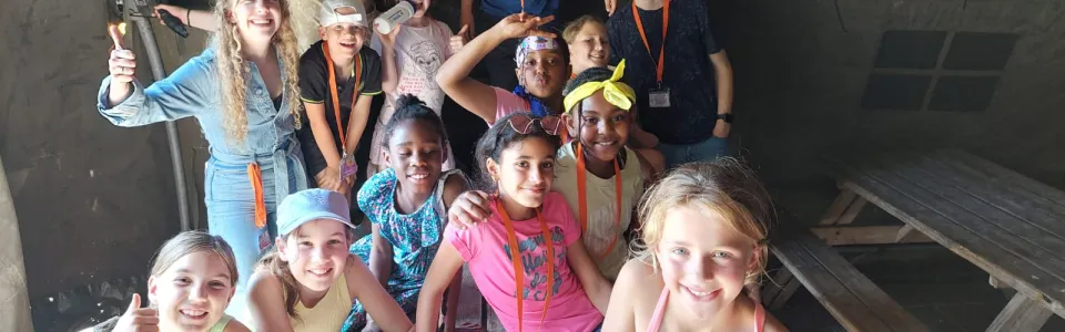Lachende kinderen en leiding poseren samen in een tent