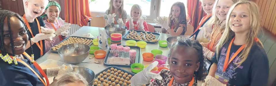 Lachende kinderen rollen samen snoepballetjes tijdens het kamp