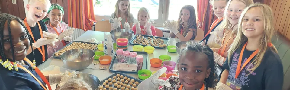 Lachende kinderen rollen samen snoepballetjes tijdens het kamp