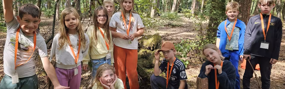 Kinderen poseren samen tijdens een vrolijke bosactiviteit op kamp.