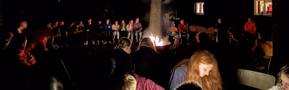 Deelnemers rond een kampvuur in het donker