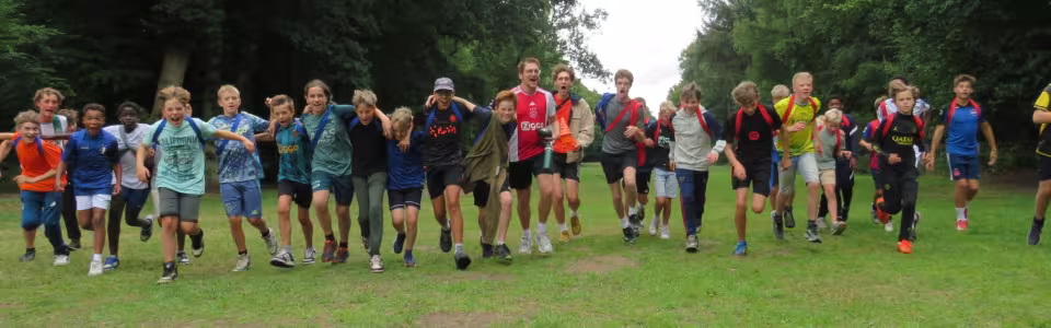 Deelnemers staan in een grote kring op het grasveld