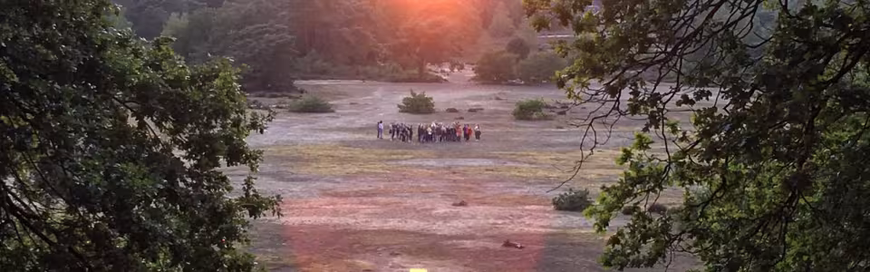 Zonsondergang boven een zandvlakte met een groep deelnemers