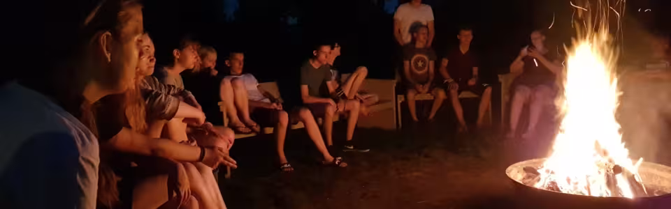 Jongeren zitten 's avonds rond een vuurkorf