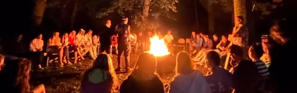 Jongeren zitten samen rond een knisperend kampvuur in het bos