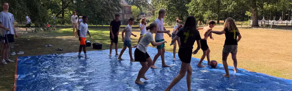 Tieners spelen samen op een zeepgladde mat in het park