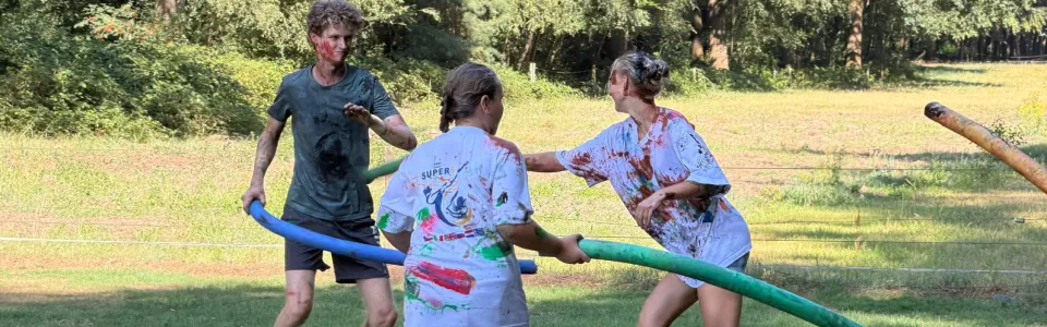 Tieners spelen lachend een verfspel met schuimstokken op Brugkamp 2