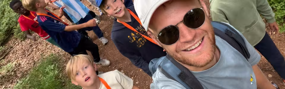 Kampleider maakt een selfie met deelnemers in het bos