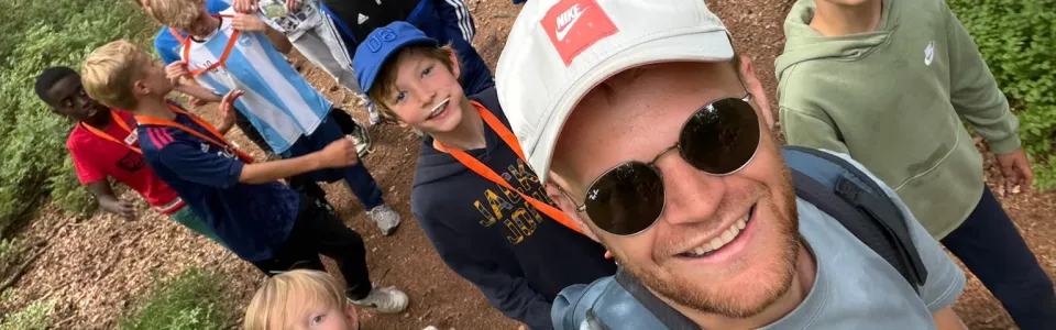 Kampleider maakt een selfie met deelnemers in het bos