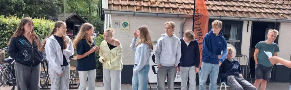 Deelnemers staan te praten bij het kampgebouw