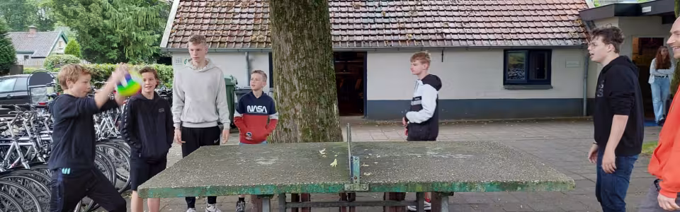 Deelnemers spelen tafeltennis bij het kampgebouw
