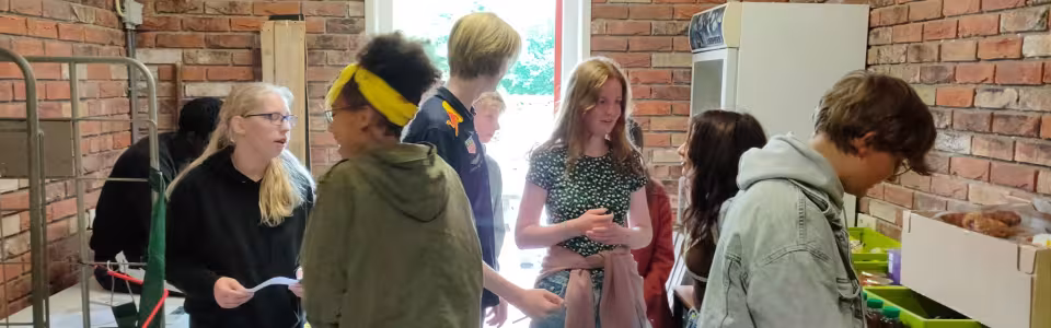 Deelnemers vullen bekers in een ruimte met bakstenen muur