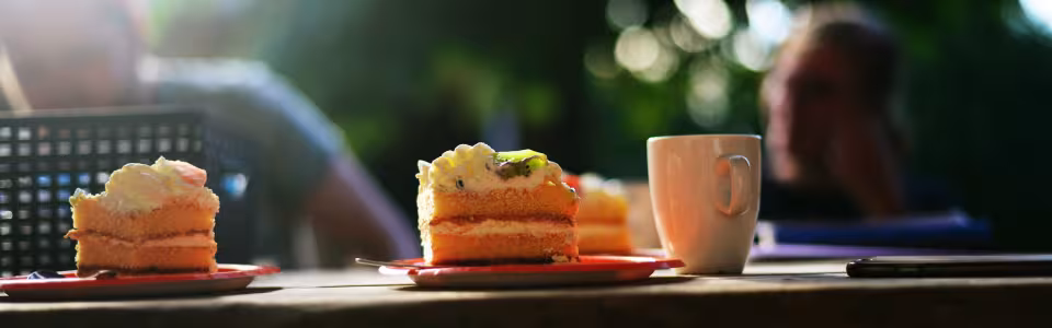 Cake en een beker op een houten tafel buiten