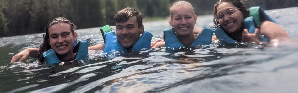 Deelnemers met zwemvest in het water van een bergmeer