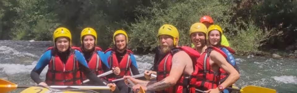 Deelnemers met helm en zwemvest in een raft